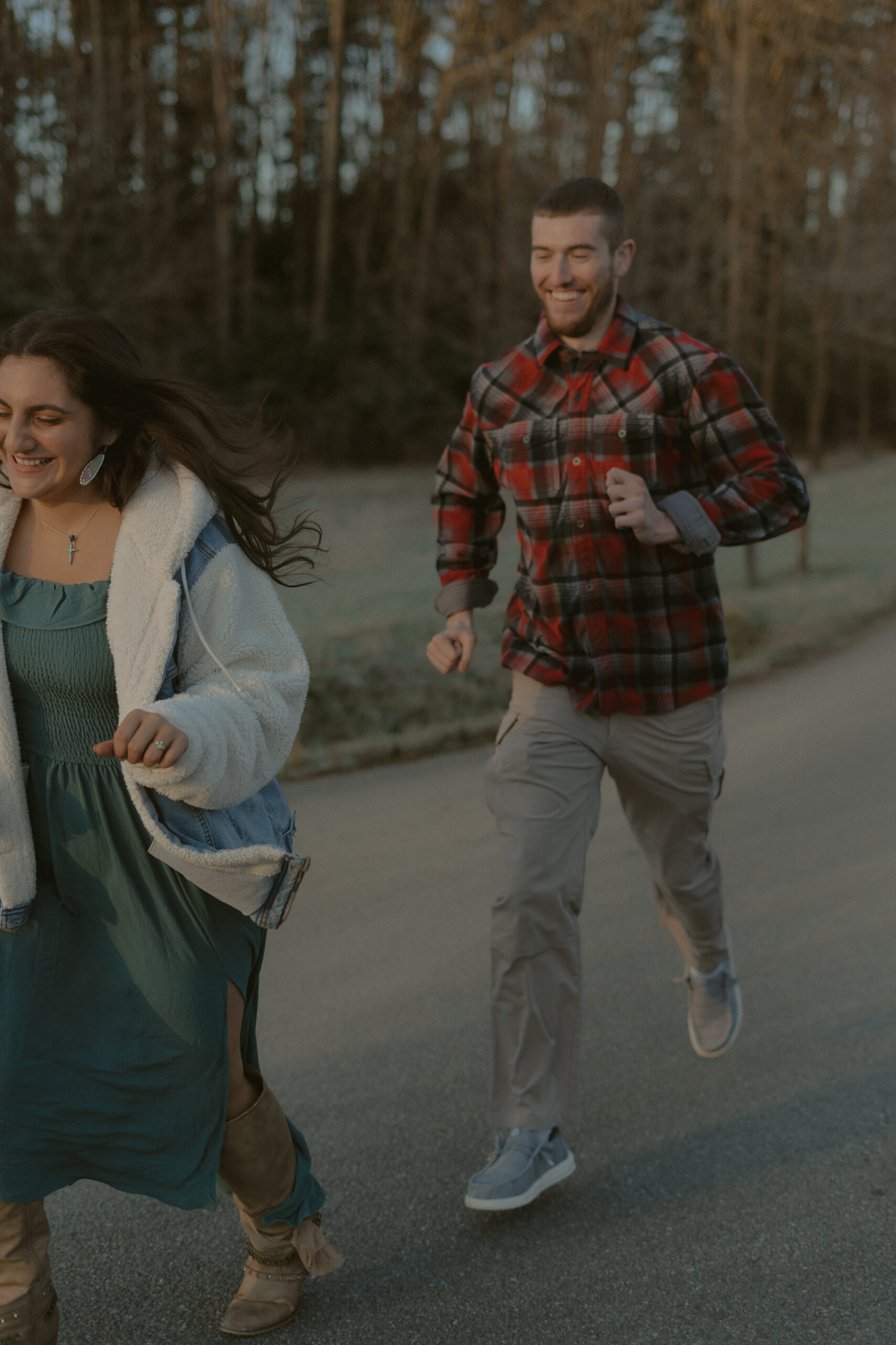 A newly engaged couple chase each other during a photo session.